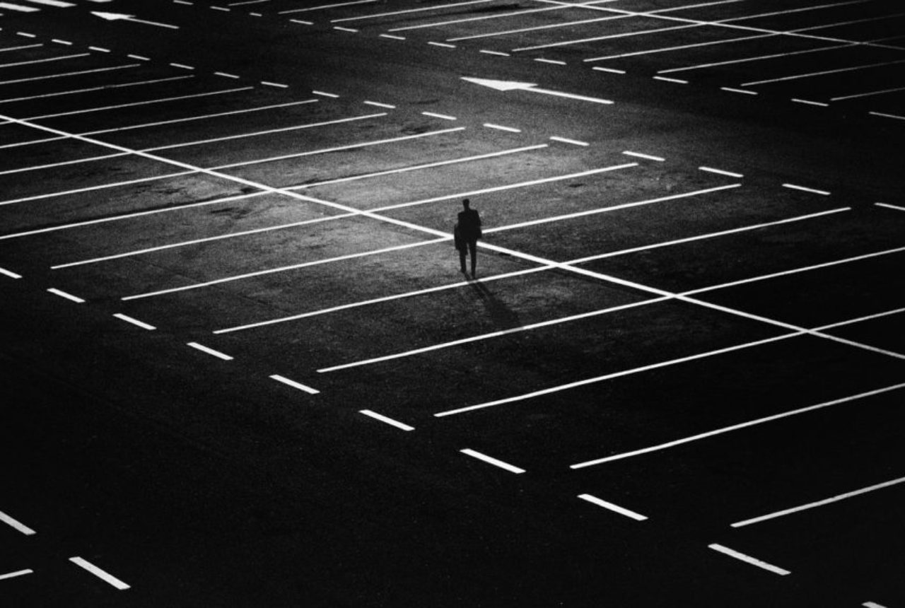 man-walking-in-empty-parking-lot-night