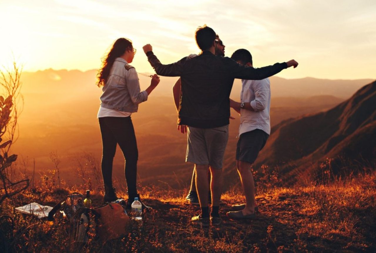 four-person-standing-at-top-of-grassy-mountain-697244