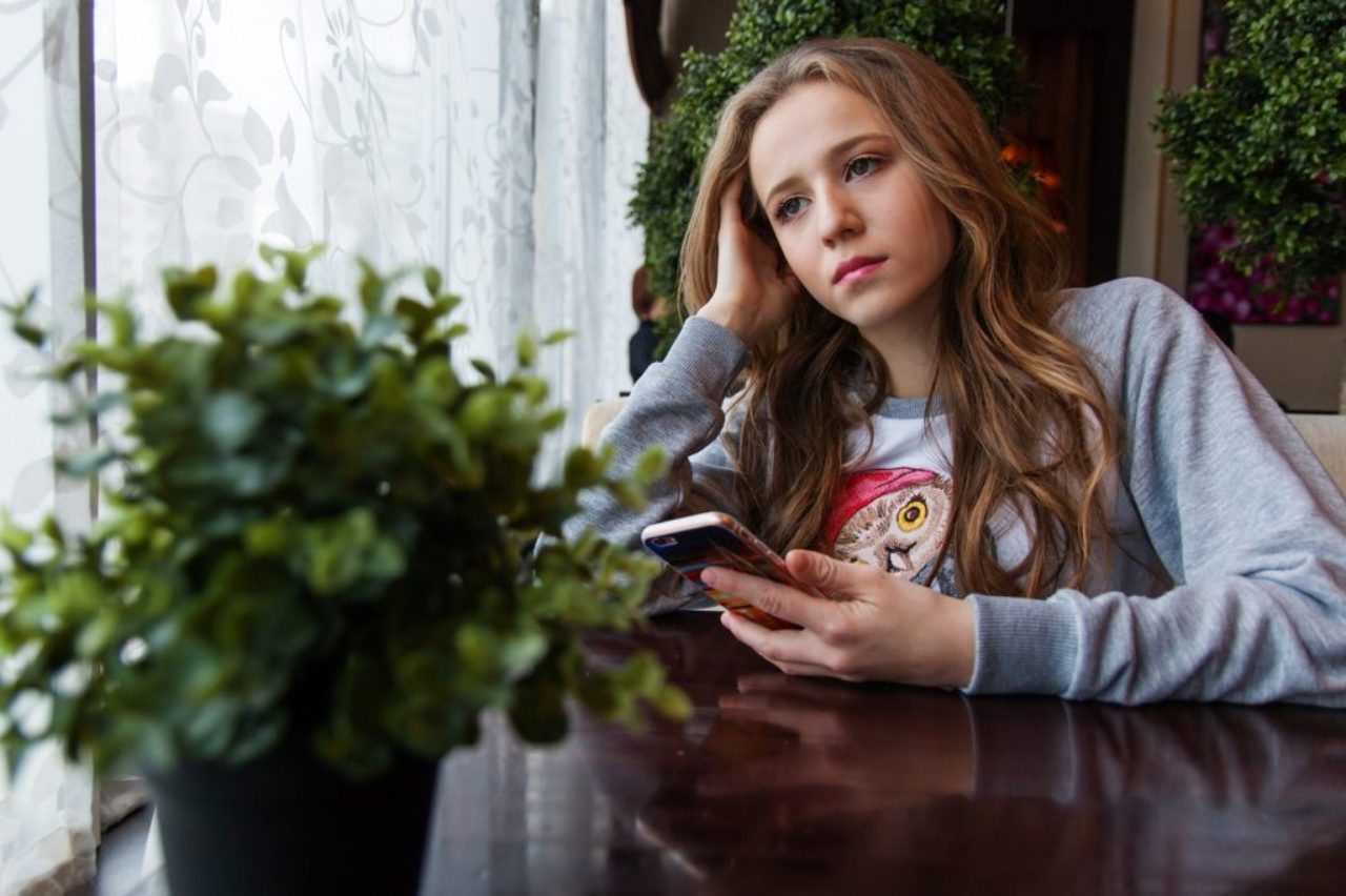 girl-in-thought-at-table-with-smartphone