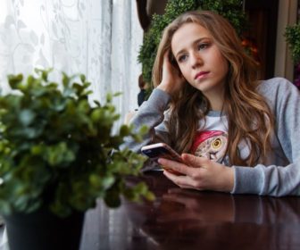 girl-in-thought-at-table-with-smartphone