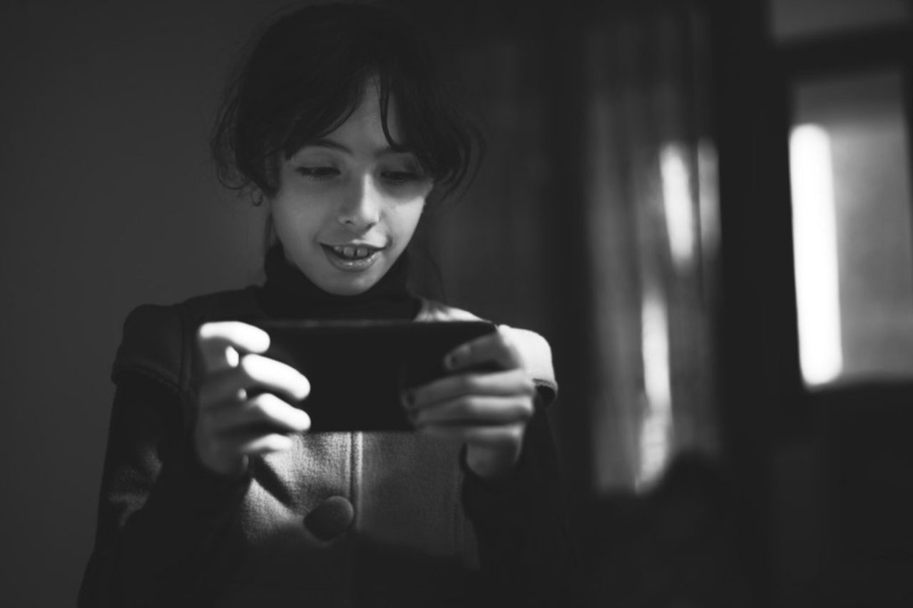 grayscale-photography-of-girl-using-smartphone-1701278