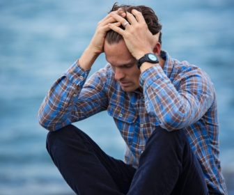 man-in-blue-and-brown-plaid-dress-shirt-touching-his-hair