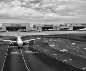 gray-scale-of-air-plane-on-runway-under-cloudy-day