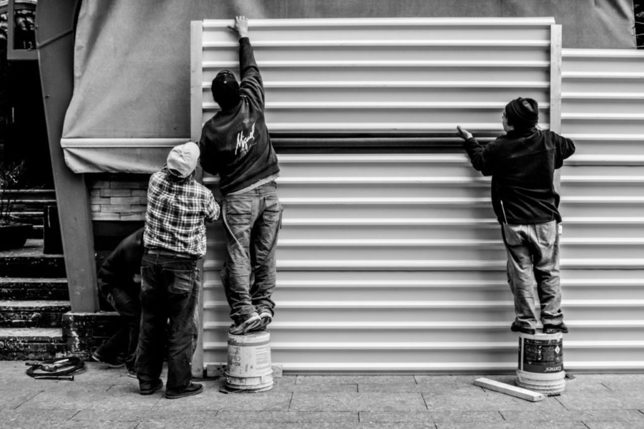 grayscale-photo-of-three-men-arranging-metal-wall-959325