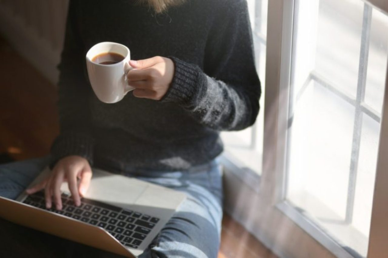 woman-using-laptop-while-holding-a-cup-of-coffee-3759083/