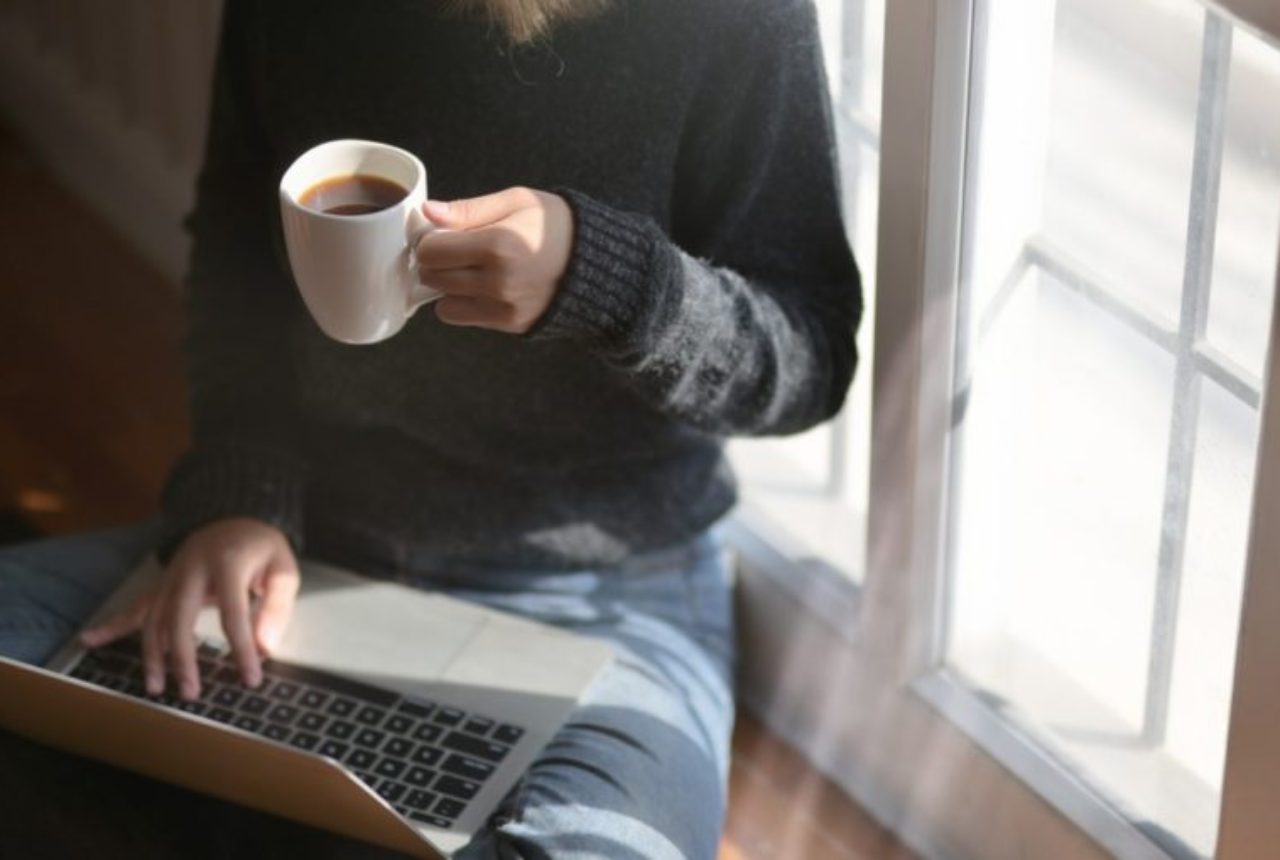 woman-using-laptop-while-holding-a-cup-of-coffee-3759083/