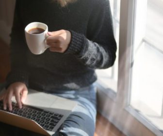 woman-using-laptop-while-holding-a-cup-of-coffee-3759083/