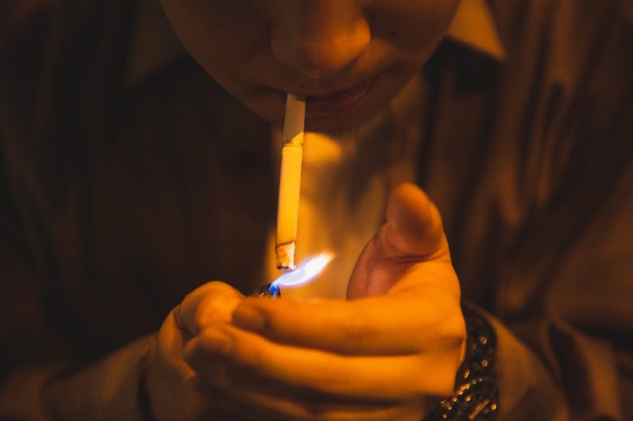 man-lighting-cigarette-for-smoking-in-light-of-lamp