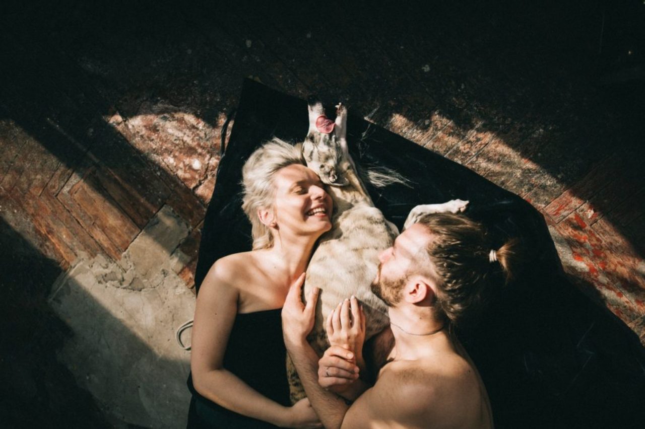 couple-lying-down-and-hugging-their-dog